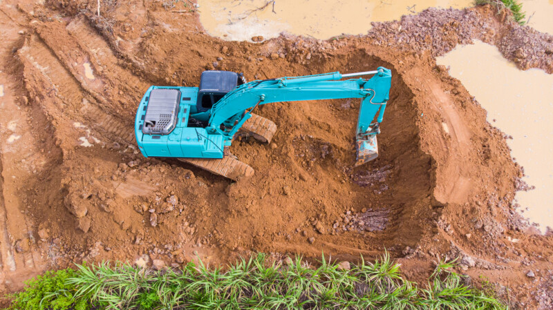 Backhoe loading soil into a truck then the truck carries soil for sale.